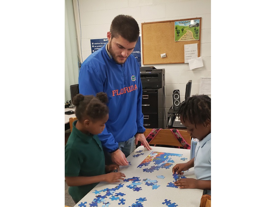 GYAC 1st grade teacher assisting students with a puzzle